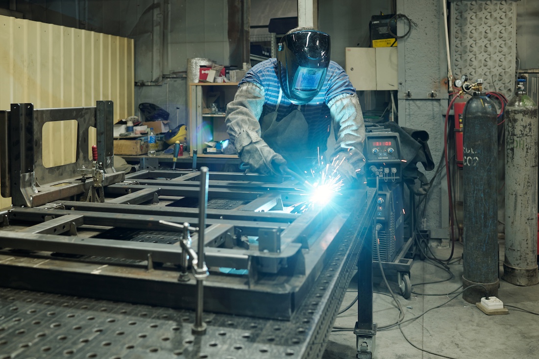 Welder working on a steel fabrication piece in a workshop